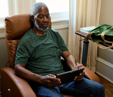Bob, a patient living with early Alzheimer's, sitting on a chair, looking at his tablet