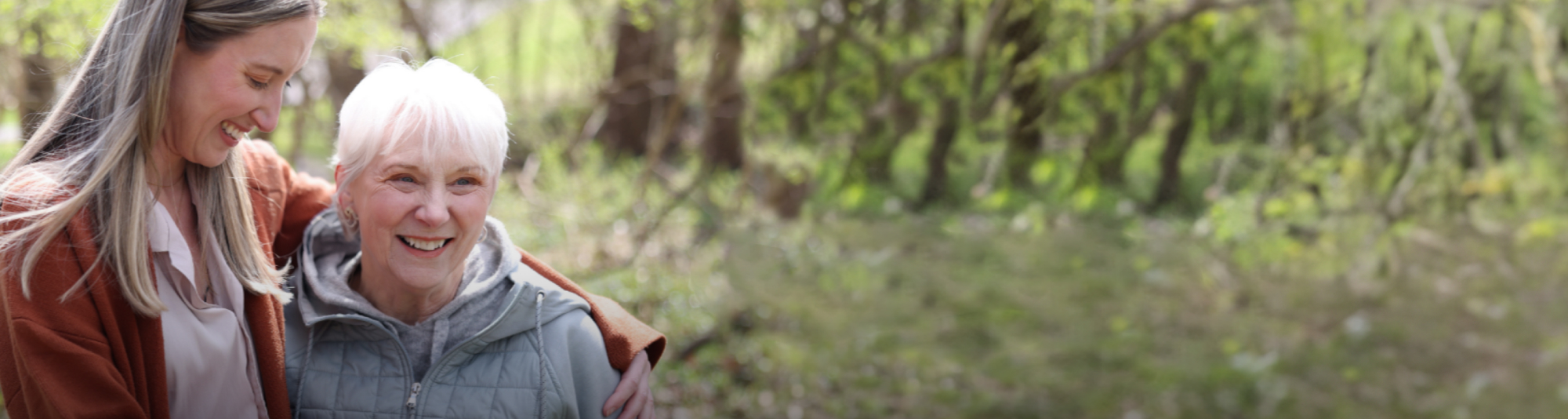 Nina, a patient living with early Alzheimer's, and her daughter, Megan, spending time outdoors and smiling