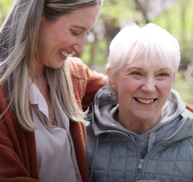 Nina, a patient living with early Alzheimer's, and her daughter, Megan, spending time outdoors and smiling