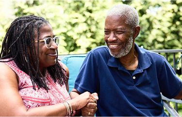 Bob, a patient living with early Alzheimer's, and his wife, Cynthia, sitting and smilings