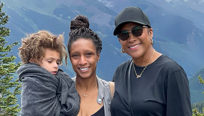 Kamala, a patient living with early Alzheimer's, her grandson, and her daughter, Jessica, pose together with mountains