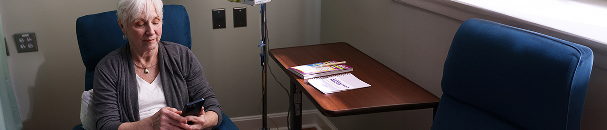 Nina sitting down, using her phone at an infusion center