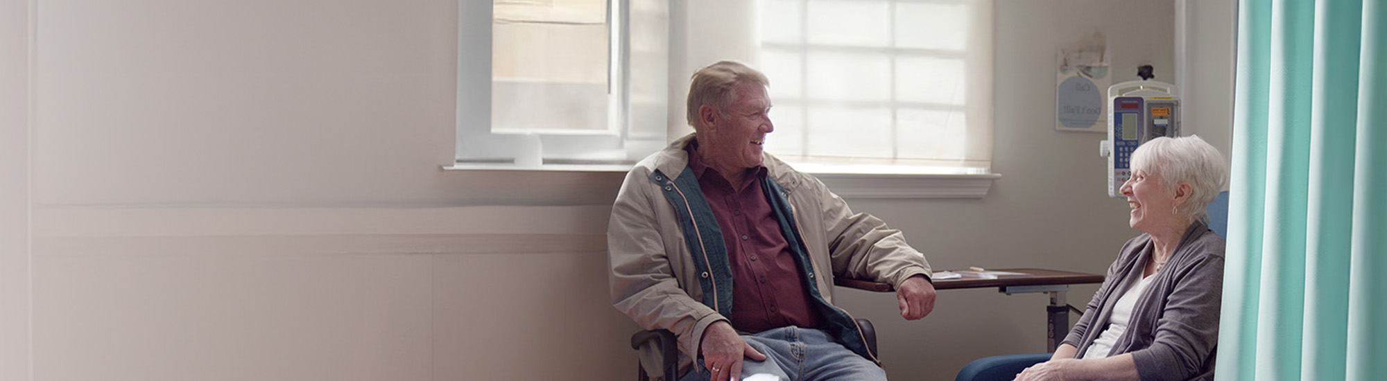 Nina and her husband, Greg, smiling at each other at an infusion center