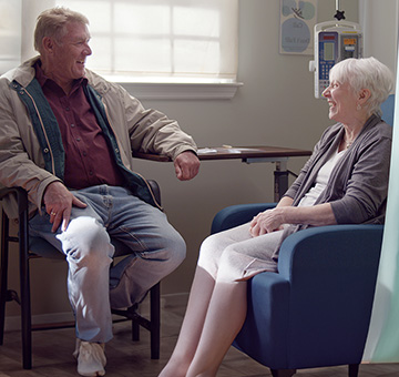 Nina and her husband, Greg, smiling at each other at an infusion center