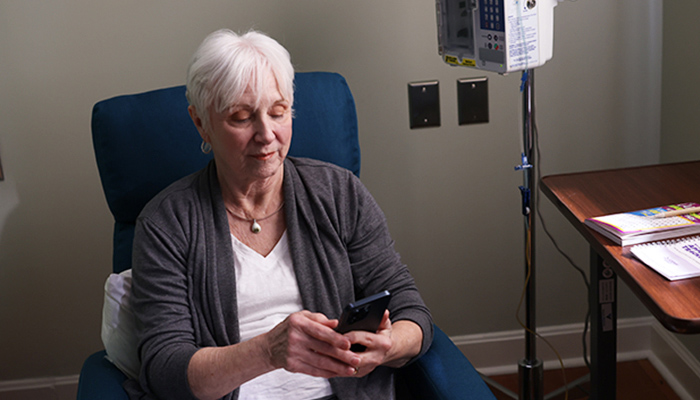 Nina, una paciente con Alzheimer temprano, sentada, usa su teléfono.