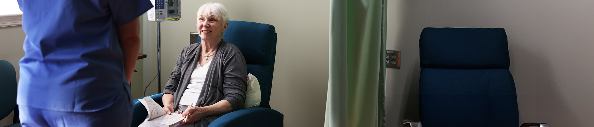 Nina, a patient living with early Alzheimer's, sitting down at an infusion center