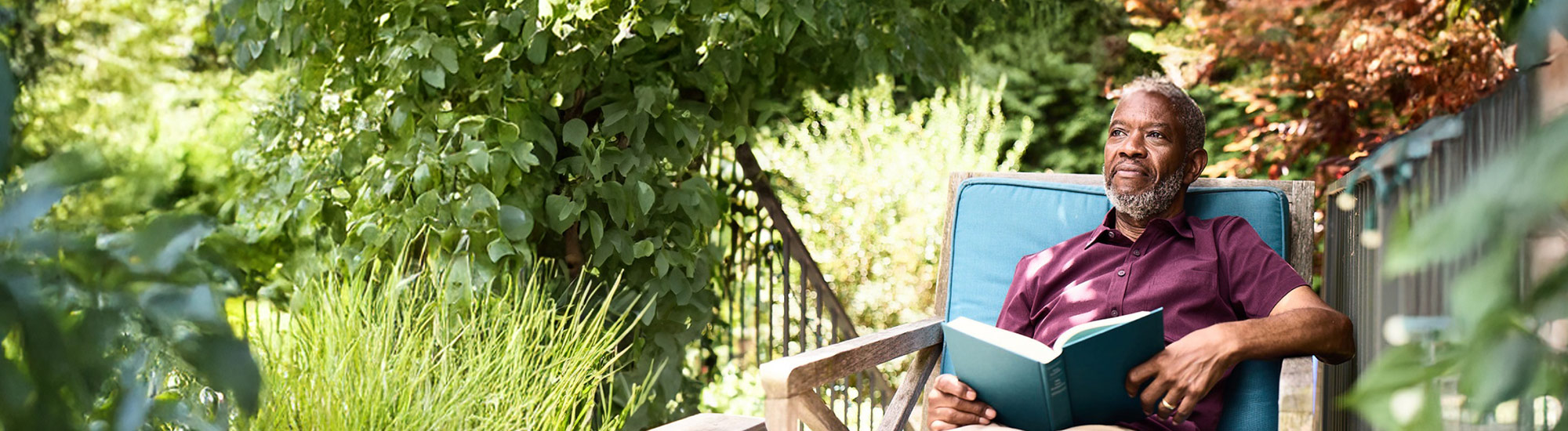 Bob sits relaxed in a chair, surrounded by lush greenery and sunlight