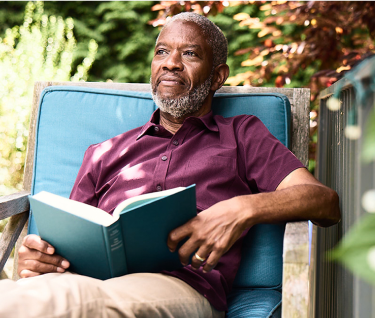 Bob sits relaxed in a chair, surrounded by lush greenery and sunlight