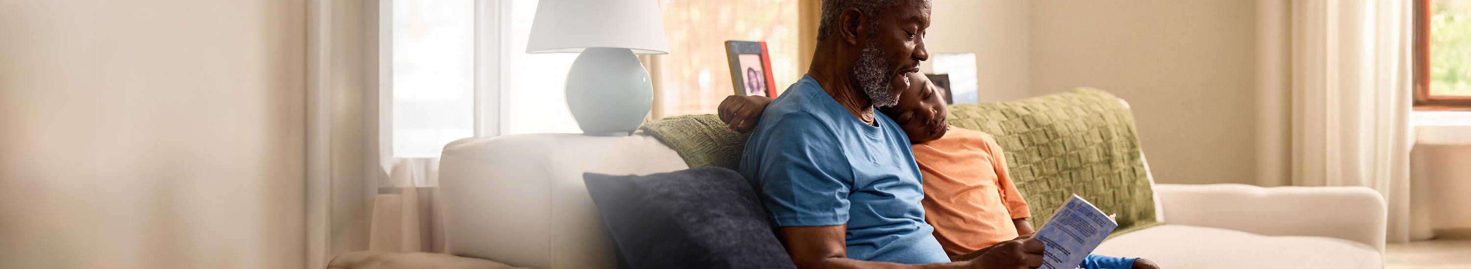 Bob, a patient living with early Alzheimer's, sitting down, reading a book with his grandson