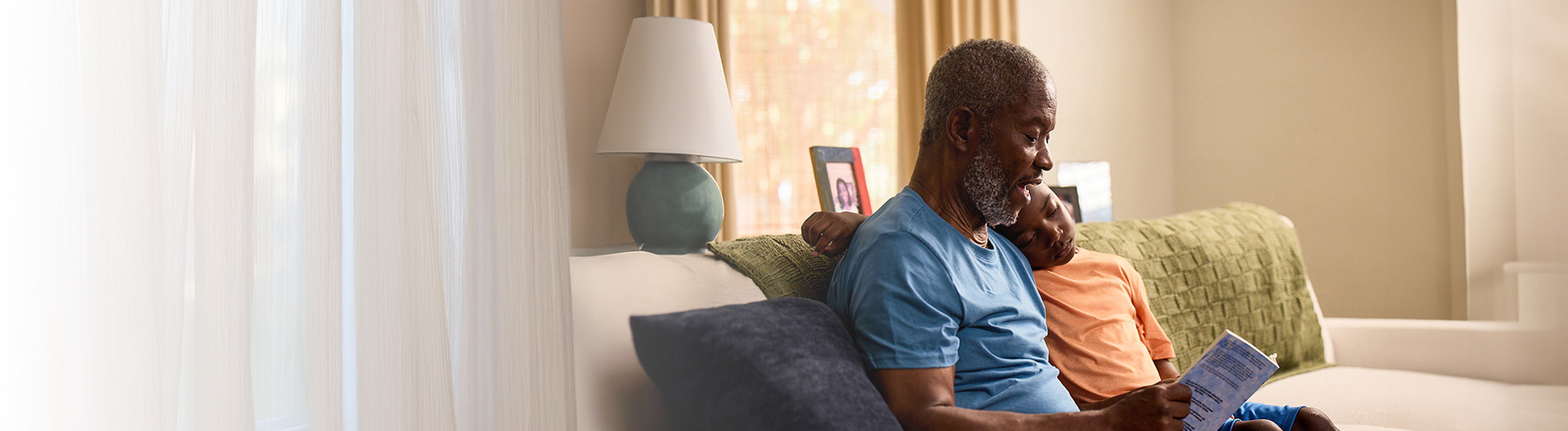 Bob sitting down, reading a book with his grandson