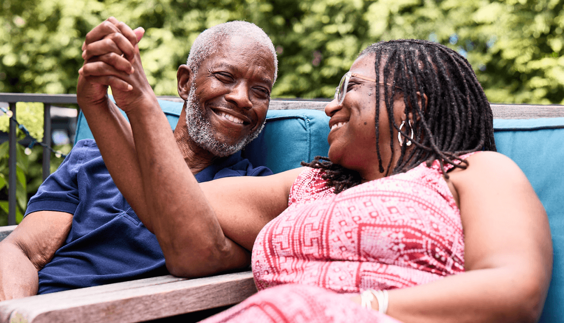 Bob, a patient living with early Alzheimer's, and his wife, Cynthia, outdoors holding hands and smiling