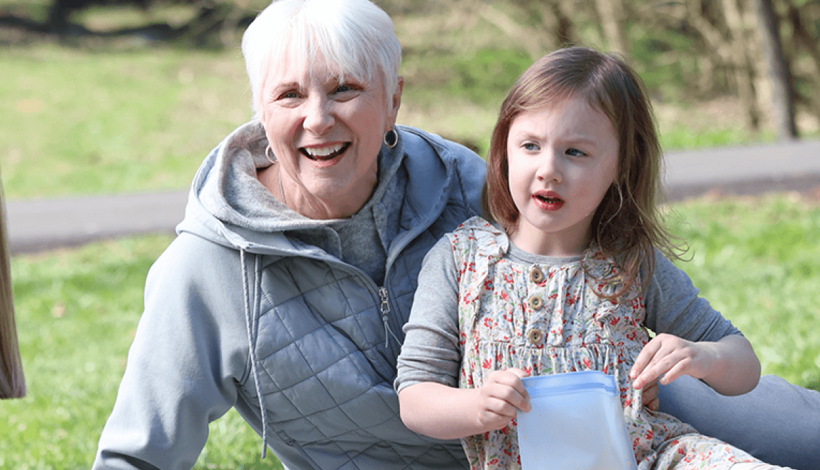 Nina, a patient living with early Alzheimer's, and her granddaughter, outdoors and smiling